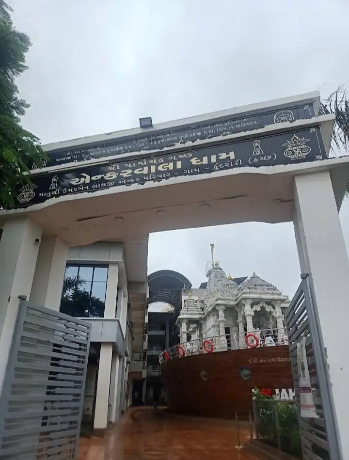 Entrance gate with Gujarati signage leading to a white marble temple