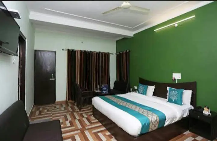 Guest room with double bed, green feature wall and sofa