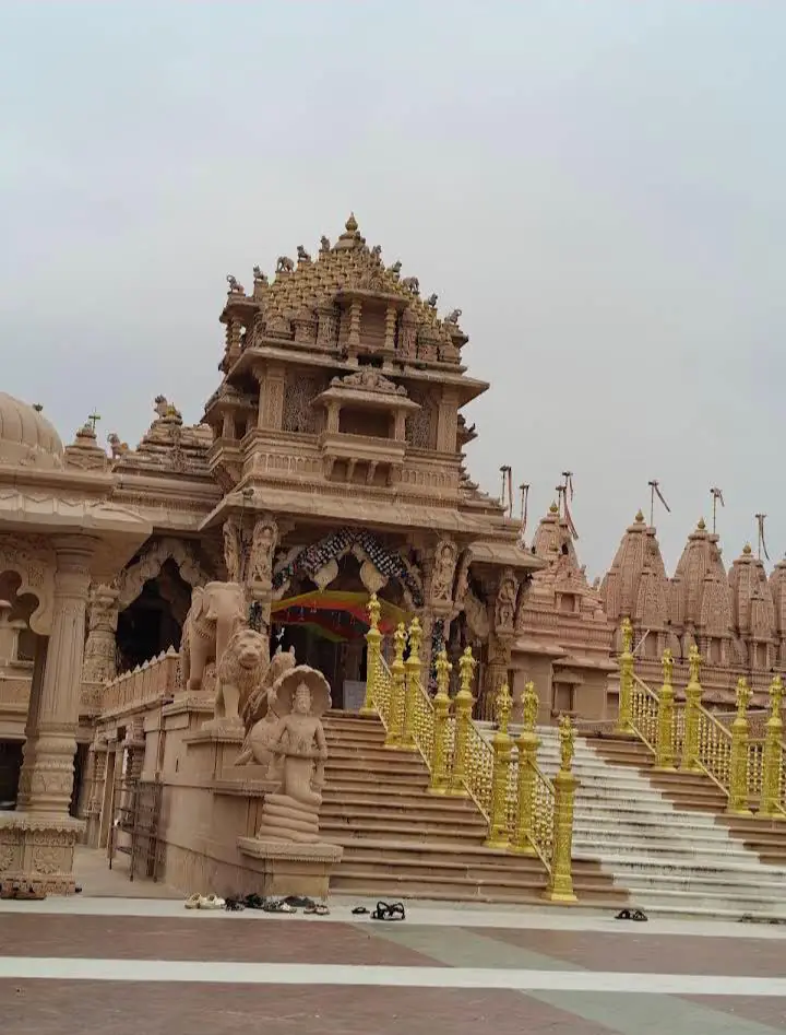 Pink sandstone temple with golden stair railings in Shankheshwar